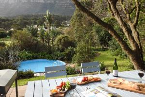 a table with a plate of food and wine glasses at Kairos Lodge in Hout Bay
