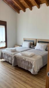 2 Betten in einem weißen Zimmer mit Holzböden in der Unterkunft Casa de Aldea EL AVELLANU in Bierces