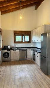 eine große Küche mit Edelstahlgeräten und Holzdecken in der Unterkunft Casa de Aldea EL AVELLANU in Bierces