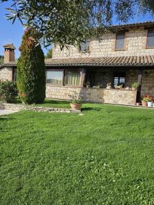 Il Casale del Conte في Fratta Todina: منزل أمامه حديقة خضراء