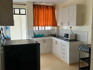 een keuken met witte kasten en een oranje gordijn bij chomama homes in Ngong