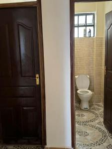 een badkamer met een toilet en een houten deur bij chomama homes in Ngong