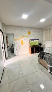 a bedroom with a mural of a beach and a television at Kitnet do Recanto em Guriri in São Mateus