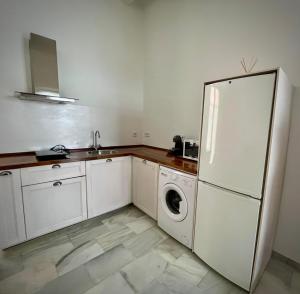 a kitchen with a refrigerator and a washing machine at Casa Palacio Caballeros in Sanlúcar de Barrameda +5 photos