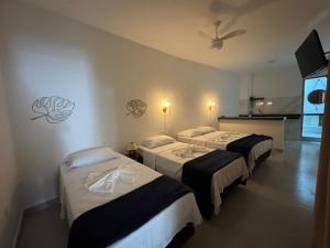 a hotel room with three beds and a fan at Hey Mar Suites in Arraial do Cabo