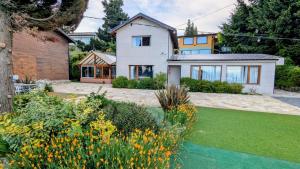 a large white house with a garden at Apart Hotel Bungalows Matute in San Carlos de Bariloche
