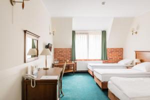 ein Hotelzimmer mit drei Betten und einem Schreibtisch in der Unterkunft Hotel Szymbark in Szymbark