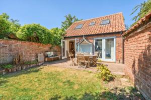 a brick house with a patio with a table and chairs at Edinburgh House in Burnham Market