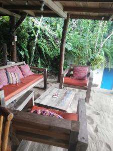 a porch with two benches and a table with pillows at casa colibri cañón de rio dulce in Lívingston