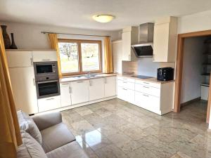 Una cocina con gabinetes blancos y una ventana grande. en Schiestl, en Ramsau im Zillertal