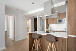 eine Küche mit einer Theke und 2 Hockern in der Unterkunft AVG Numa Guilhou 4 in Gijón