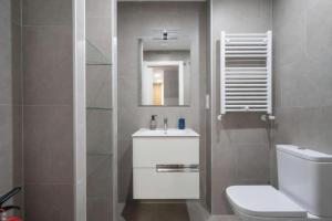 ein Badezimmer mit Toilette, Waschbecken und Spiegel in der Unterkunft AVG Numa Guilhou 4 in Gijón