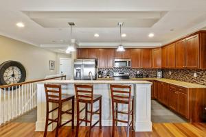 eine Küche mit Holzschränken und eine Insel mit Barhockern in der Unterkunft CSC3H Rum Runner in Kill Devil Hills