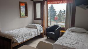 a room with two beds and a chair and a window at Apart Hotel Bungalows Matute in San Carlos de Bariloche +80 photos
