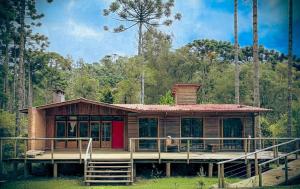 a house with a large deck in the woods at Recanto Bellagio in Campos do Jordão