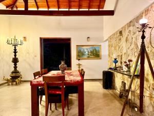 Un comedor con una mesa roja y un trípode. en Lotus and Moon, en Habaraduwa Central