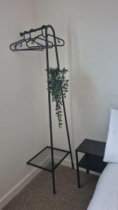 a plant on a iron stand next to a bed at Cockermouth Cottage - Lakes - Parking in Cockermouth