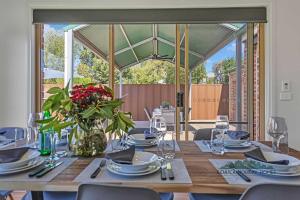 a table with plates and glasses and a vase of flowers at Central Echuca Escape, Heated Pool, 3 BDR in Echuca