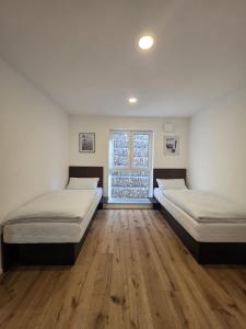 two beds in a room with wooden floors and a window at Malerischer Panoramablick Worgberg in Ingelfingen