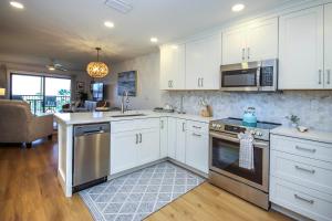 a kitchen with white cabinets and stainless steel appliances at 3rd Story Sanibel Condo With Coastline Views 3C3 in Sanibel