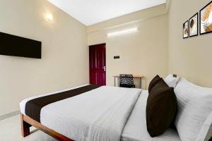 Hotel O Moonlight Residency في Vettutura: غرفة نوم بها سرير وتلفزيون على الحائط