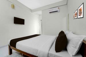 Hotel O Moonlight Residency في Vettutura: غرفة نوم بسرير بجدران بيضاء
