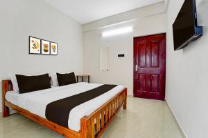 Hotel O Moonlight Residency في Vettutura: غرفة نوم بسرير وباب احمر