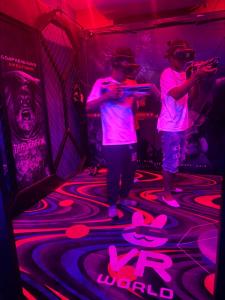 4LoyaltyRecords2storeyQueensuite في كينغستون: رجلان يقفان في غرفة بها أضواء نيون