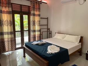 a bedroom with a bed with a blue blanket and a window at Ivy Villa - Tangalle in Tangalle
