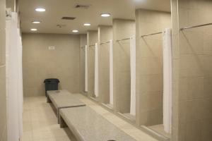 a row of stalls in a bathroom with a bench at Travohostal Monterrey Historico in Monterrey