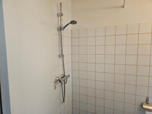 un bagno con doccia e piastrelle bianche di Cozy One Room Apartment a Roskilde