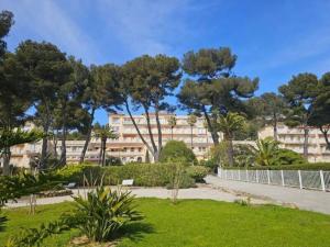 ein Park mit Bäumen und ein Gebäude im Hintergrund in der Unterkunft Beautiful apartment in Mont des Oiseaux in Hyères