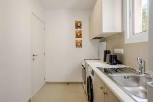 a white kitchen with a sink and a stove at Urban Bay Studios in Limassol +35 photos