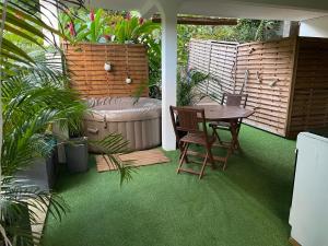 a patio with a table and a bath tub at Ti bambou nature in Sainte-Anne