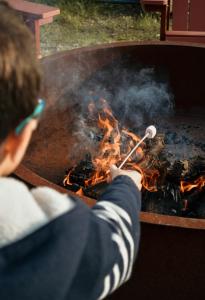 a man cooking meat on a grill with a stick at Canhoto Douro in Marco de Canaveses