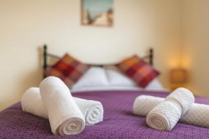 a group of rolled towels on a purple bed at Spacious Modern 5 bedroom home near Heathrow Windsor in Canvey