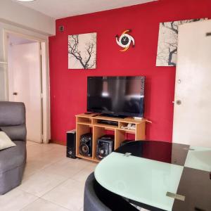 a living room with a tv and a red wall at Comfortable Independent Apartment Downtown Ccs in Caracas +22 photos
