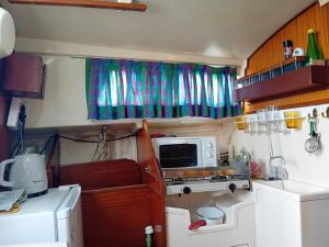 a small kitchen with a microwave and a refrigerator at Voilier au Port de Perros-Guirec in Perros-Guirec