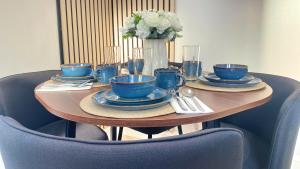 a table with blue cups and plates and a vase with flowers at Ready Stay Work Lodge in Birmingham
