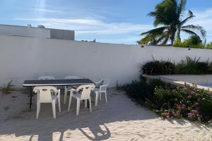 a table and chairs in the sand next to a wall at Villa del Mar, un espacio funcional y bien ubicado in Progreso