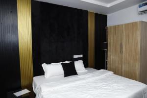 a bedroom with a white bed with a black wall at Olabanji Royal Garden Hotel in Ibadan