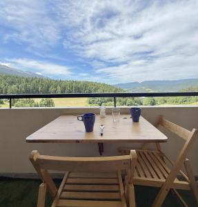een houten tafel en stoelen op een balkon met uitzicht bij Métamorphose Au Sommet in Prénatier
