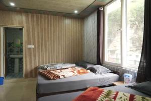 a bedroom with two beds and a window at Hotel Chauhan Palace in Uttarkāshi