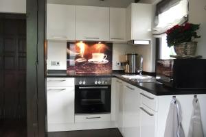 eine Küche mit weißen Schränken und einem Herd mit Backofen in der Unterkunft Ferienhaus zum Frankenblick in Sonneberg