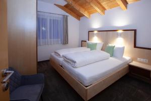 a bedroom with a large white bed with green pillows at Alpina Appartements in Nauders