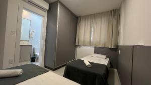 una piccola stanza con due letti e una finestra di Aptos em prédio a 90 m da praia de Perequê - RIHs a Perequê