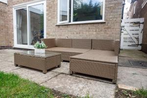 ein Korbsofa und ein Tisch vor einem Haus in der Unterkunft Home from Home in Leicester