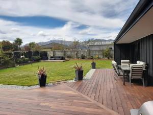 a patio with chairs and a table and a lawn at Beautiful Home in Lake Hawea in Lake Hawea