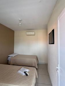 a hotel room with two beds and a television at Hotel Portal do Eden in Sorocaba