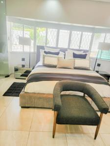 una camera da letto con un letto grande e una sedia di Hudson Haven Bed & Breakfast a Pietermaritzburg